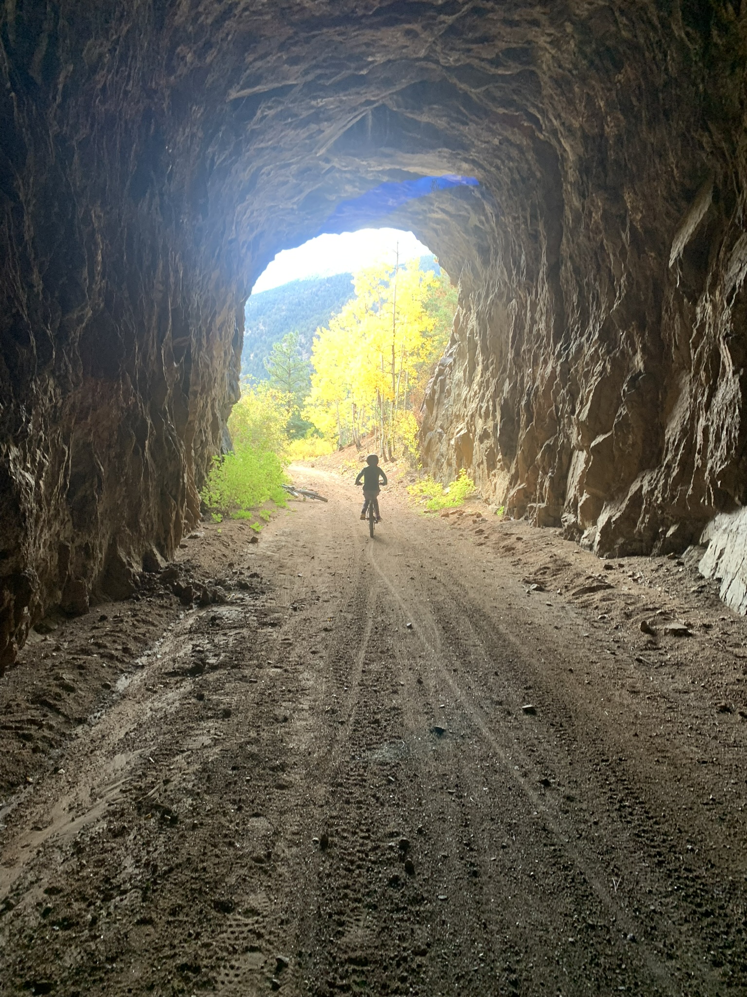 Cyclist riding through a canyon tunnel toward light in South Cheyenne Canyon.
